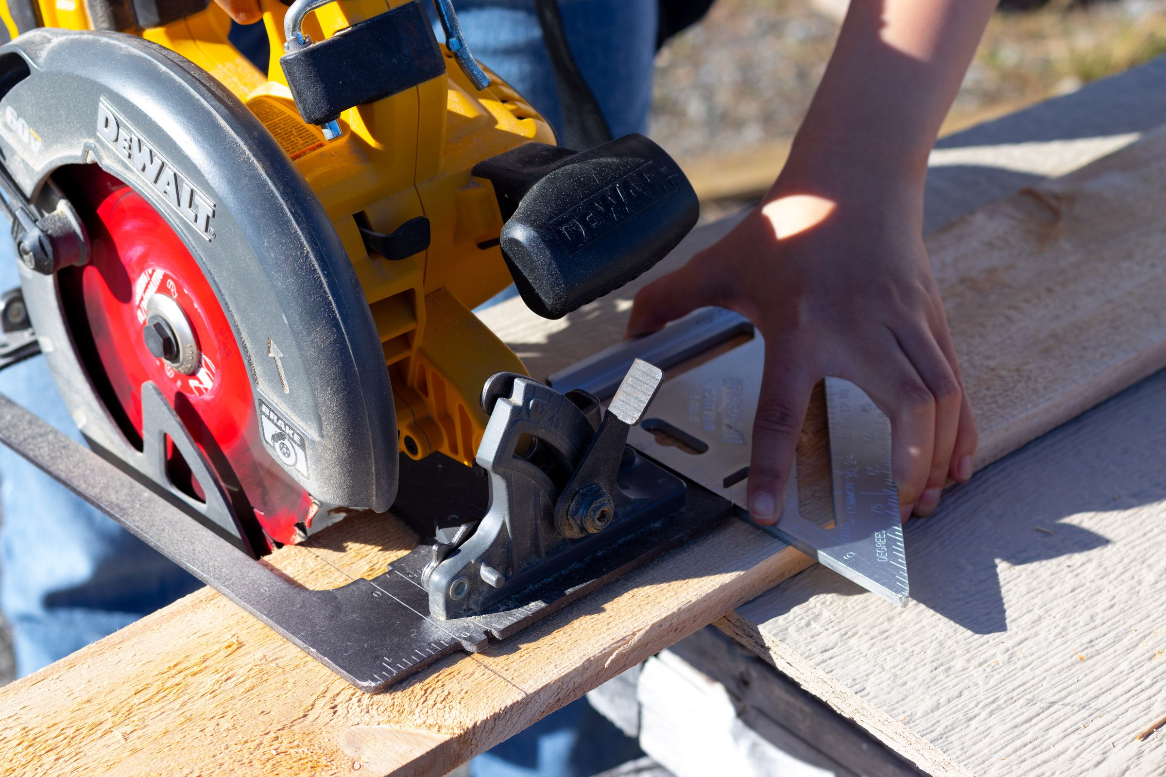 A carpenter cutting a board with a circular saw and a speed square